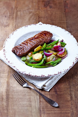Beef steak with oven roasted vegetables on rustic wooden background.