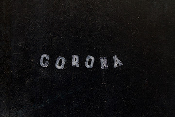 Corona als weisser Schriftzug vom Stempel auf schwarzer Tafel