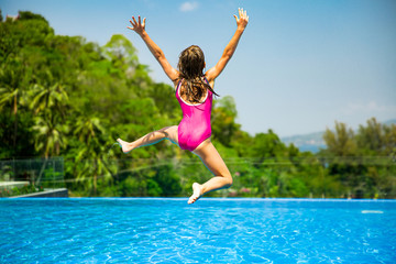 Excited funny little girl jumping to the swimming pool. Happy summer vacation