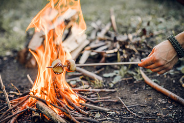 A man roasts marshmallows on a fire near the tent