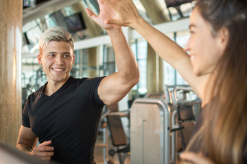 Fototapeta na wymiar Cheerful couple doing cardio exercises on a treadmill and giving high-five to each other