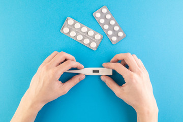 Hands hold a set of hygienic antiseptics and medications on a blue background.