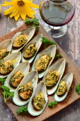 Baked green mussels with garlic butter herb sauce served with glass of red wine
