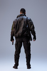 back view of cyberpunk player holding gun and standing on grey
