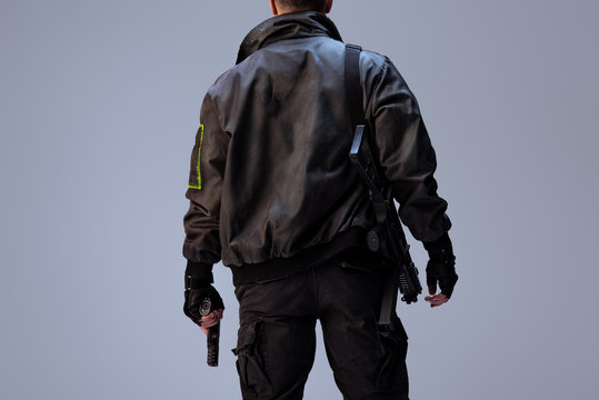 back view of cyberpunk player holding gun while standing isolated on grey