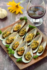 Baked green mussels with garlic butter herb sauce served with glass of red wine
