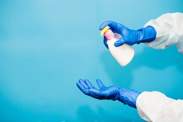 Person hand in blue glove hold soap bottle isolated on blue background
