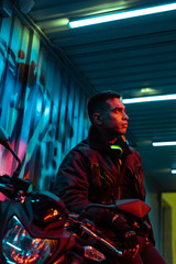selective focus of mixed race cyberpunk player near motorcycle
