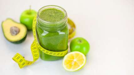 Healthy green smoothie with apple, spinach, lemon and measuring tape. Fitness trend - food for weight loss. Morning detox for a healthy lifestyle, ketone diet, raw food diet
