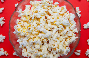 Bowl with popcorn on red background.