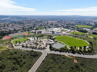 Aerial view of small community park with playground for kids in upper middle class neighborhood with residential subdivision houses during sunny day in San Diego, California, USA.