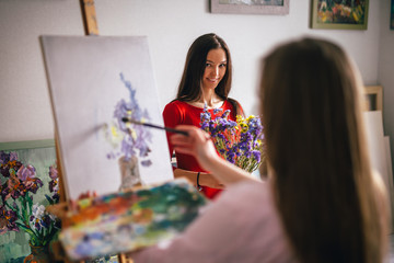 Girl artist paints his girlfriend from life in his studio