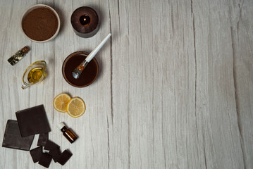 Natural cosmetics. Spa skin care, ingredients for chocolate wraps. Chocolate, cocoa powder, lemon juice, olive oil, lemon essential oil, ready-made wrap mix and spatula on a light wooden background. 