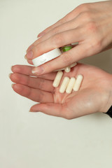 Female hand holds a tablet, capsule in hands. On white background. Pharmaceuticals. Allopathic medicine.