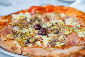 homemade pizza with ham, olives and artichoke