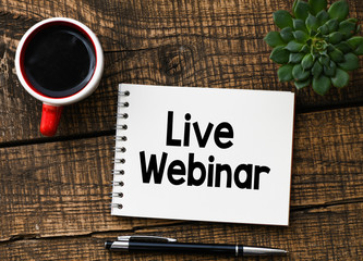 LIVE WEBINAR text inscribed in the notebook on a wooden table.