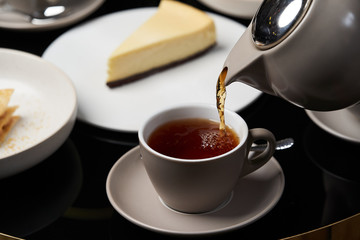 Woman hands with teapot pouring tea into cup, close-up