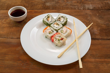 Assorted different fish rolls on a white plate.
