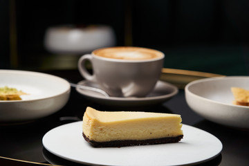Cup of tea and slice of cheesecake on white plate on table