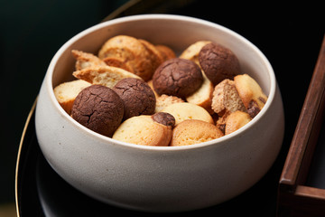 Sweet brownie cookie and biscuits in ceramic bowl on table, close up.