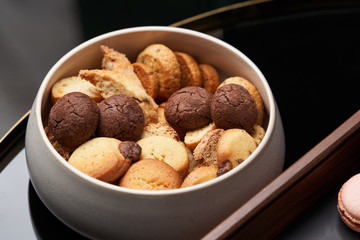 Sweet brownie cookie and biscuits in ceramic bowl on table, close up.