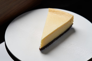 Cup of tea and slice of cheesecake on white plate on table
