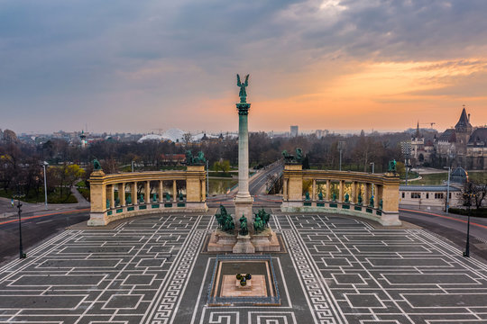 Fototapeta Budapest, Hungary - Aerial view of the totally empty Heroes' Square during the 2020 Coronavirus quarantine in the morning. Vajdahunyad Castle and City Park at background with a warm sunrise