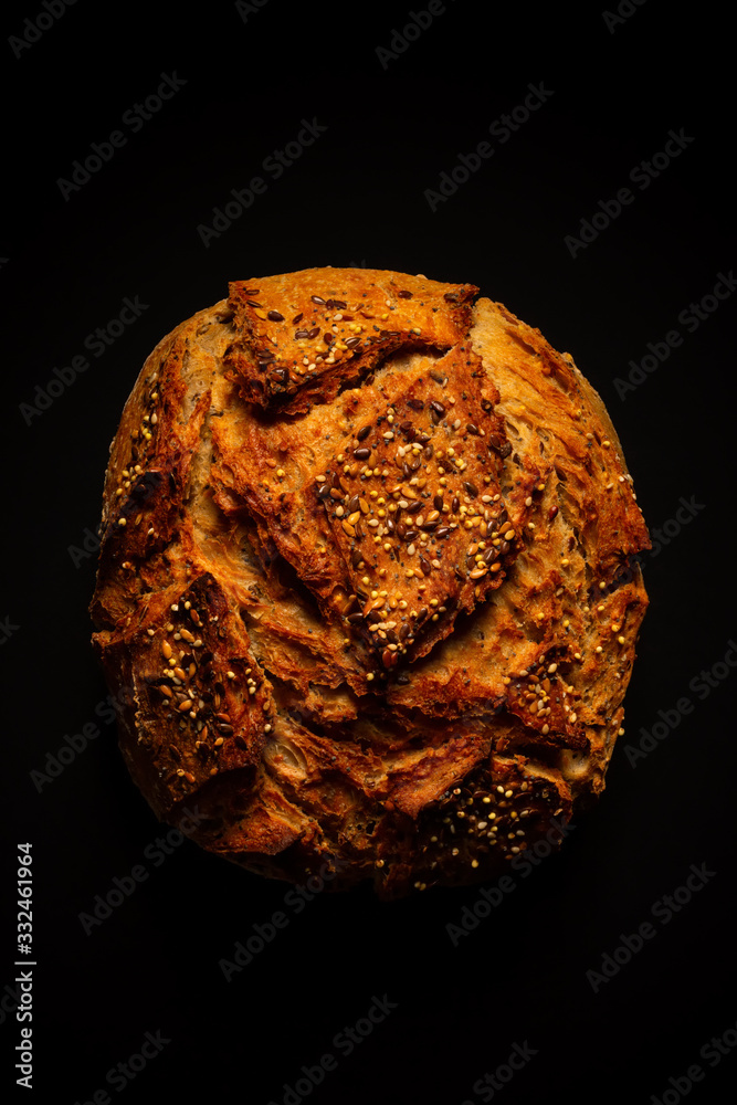 Wall mural French bread on a dark background. Rustic bread with cereals.