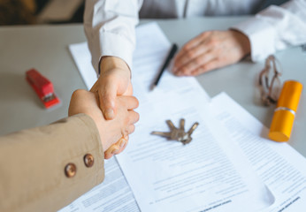 Real Estate Agent holding house key to his client after signing contract. Concept for real estate, business and properties