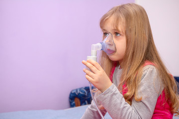 Portrait of sweet little girl using an inhaler, home therapy