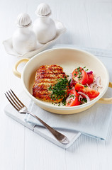 Grilled Turkey Breast with tomatoe salad. Bright wooden background.. Copy space.