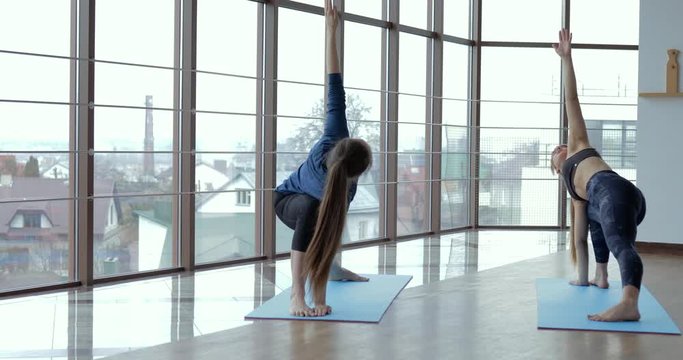 girls practice yoga in a large, light room. coach and student. sport training concept.