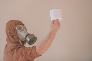 Man in a gas mask holds a roll of toilet paper. Concept: lack of toilet paper in supermarkets and local stores, the last roll of toilet paper in a shop.
