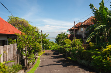 Tropical landscape overlooking the road through the village, palm trees and the ocean.