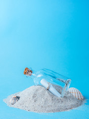 bottle with a message on sand with blue background