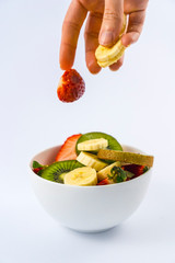 Introducing ingredients from above with a woman's hand, recipe for a fruit salad with kiwis, strawberries, bananas