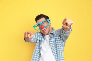Joyful man with funny glasses on yellow background. April fool's day