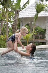 Mother and her baby girl enjoying a day at the pool, summer vacation concept	