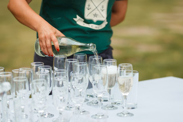 the waiter pours champagne in glasses on the street - wedding catering