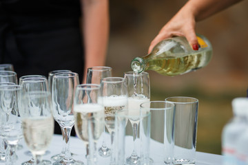 the waiter pours champagne in glasses on the street - wedding catering