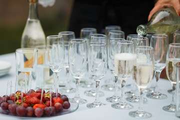 the waiter pours champagne in glasses on the street - wedding catering