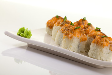 Japanese Cuisine - Appetizing Salmon Sushi Set. Philadelphia Sushi Roll - Maki Sushi with Philadelphia Cheese inside on mirror black background. Smoked salmon rolls served on a plate