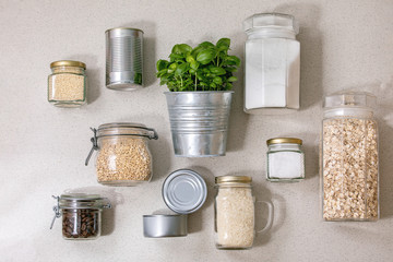 Flat lay of food supplies crisis for quarantine isolation period. Different glass jars with grains, cans of canned food, pot of basil