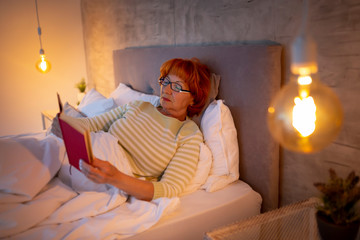 Senior woman reading in bed