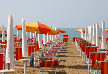 deckchairs and parasols on the beach of a tourist village withou