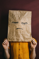 A paper bag with a sad face instead of a child's head