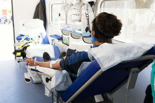 A Young Donor Sitting On An Armchair In A Mobile Blood Bank During Blood Collection. Blood Donation In A Mobile Blood Bank During Coronavirus