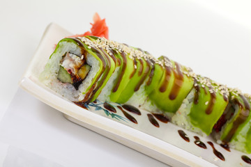 Japanese Cuisine - Appetizing Salmon Sushi Set. Philadelphia Sushi Roll - Maki Sushi with Philadelphia Cheese inside on mirror black background. Smoked salmon rolls served on a plate