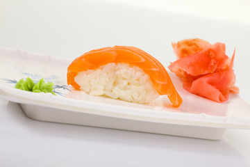 Japanese Cuisine - Appetizing Salmon Sushi Set. Philadelphia Sushi Roll - Maki Sushi with Philadelphia Cheese inside on mirror black background. Smoked salmon rolls served on a plate