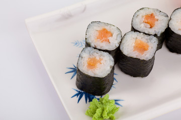 Japanese Cuisine - Appetizing Salmon Sushi Set. Philadelphia Sushi Roll - Maki Sushi with Philadelphia Cheese inside on mirror black background. Smoked salmon rolls served on a plate